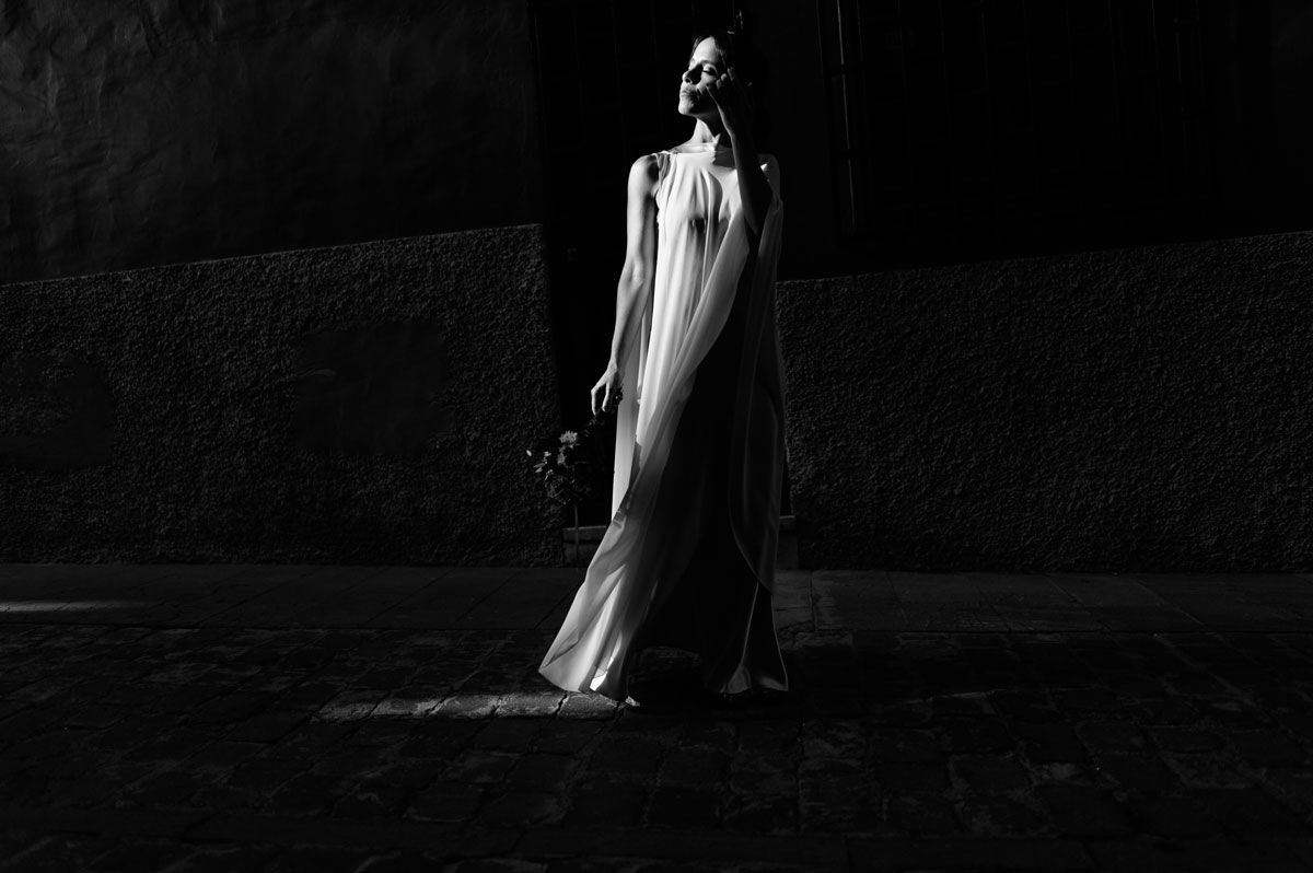 Retrato nocturno de la novia con vestido fluido, luz dramática en blanco y negro