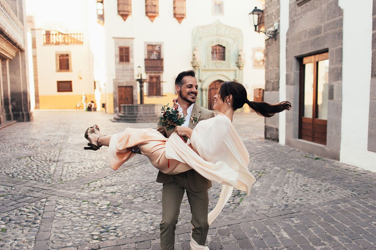 Novio llevando a la novia en brazos por las calles del casco histórico tras casarse por lo civil