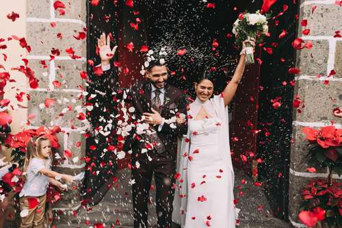 Fotógrafo de bodas en Madrid, novios saliendo de la iglesia entre pétalos de rosas