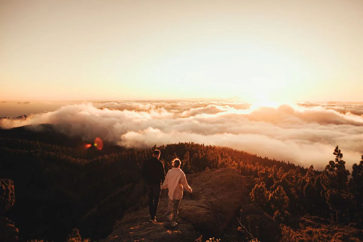 Pareja en sesion preboda al atardecer en la montana, cielo de nubes doradas