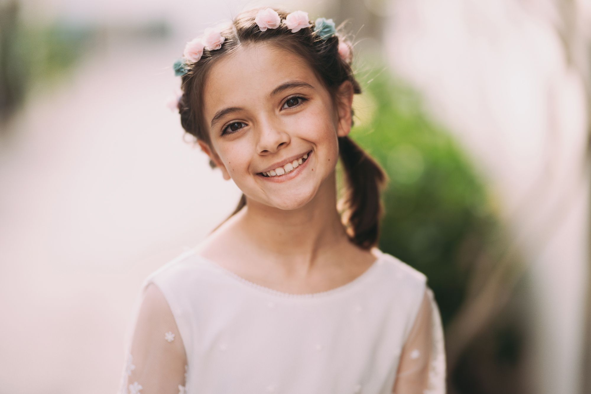 Retrato sonriente de una niña de comunión con corona de flores mirando a cámara