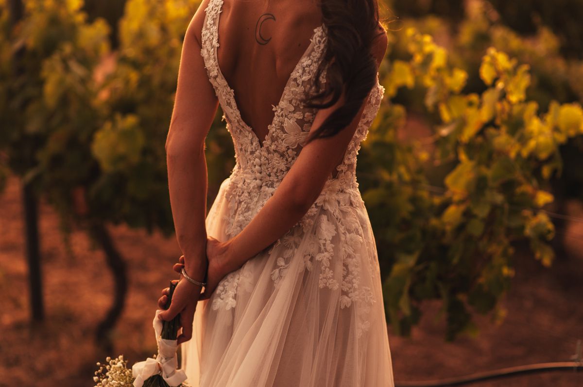 Detalle de la espalda de un vestido de novia de encaje boho, luz dorada de atardecer